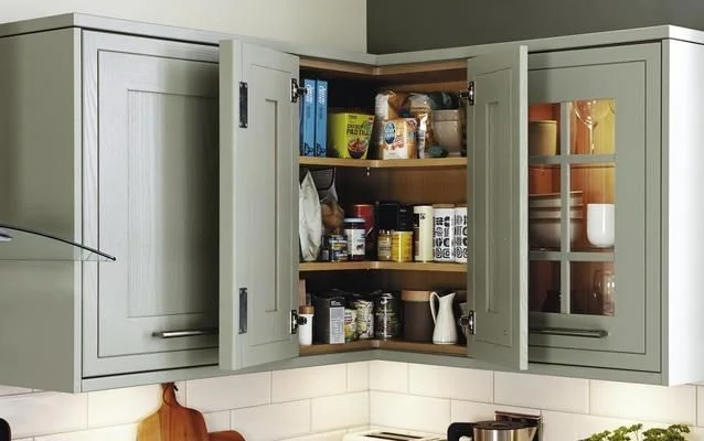 Sage green kitchen corner cabinet pantry storage solution with open bi-fold doors.