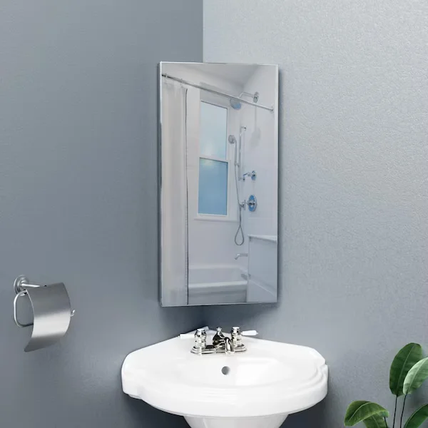 Rectangular frameless corner mirrored medicine cabinet mounted directly above a white porcelain corner pedestal sink with a classic chrome faucet against muted grey walls.