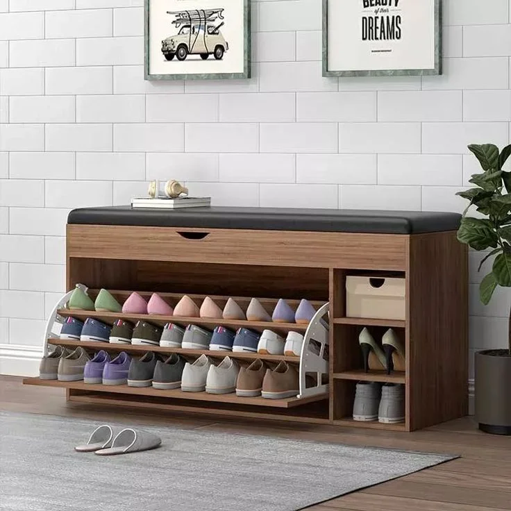 A modern wooden entryway shoe storage bench featuring a black faux leather cushioned seat, an open tipping bucket cabinet filled with organized shoes, and side shelves holding heels and a storage box.