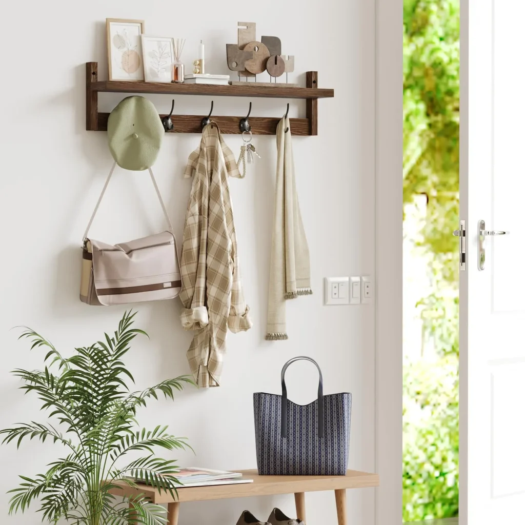 Small Entryway Organization: How to Style Wall Hooks and Shelves A wooden entryway coat rack with wall hooks and a shelf, holding a hat, a plaid shirt, keys, and a scarf next to an open front door.