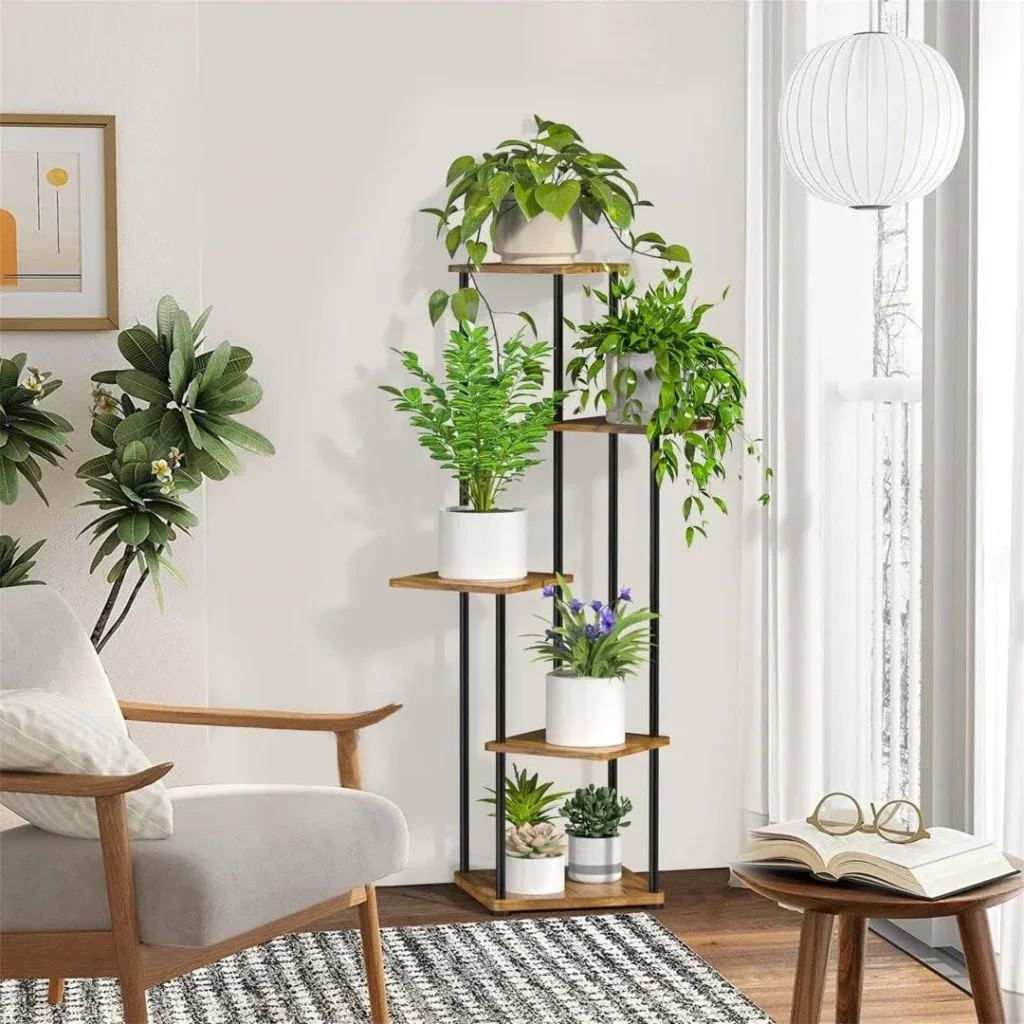Tall multi-tier indoor plant stand with wooden shelves and a black metal frame, holding various green houseplants and succulents next to a modern armchair.