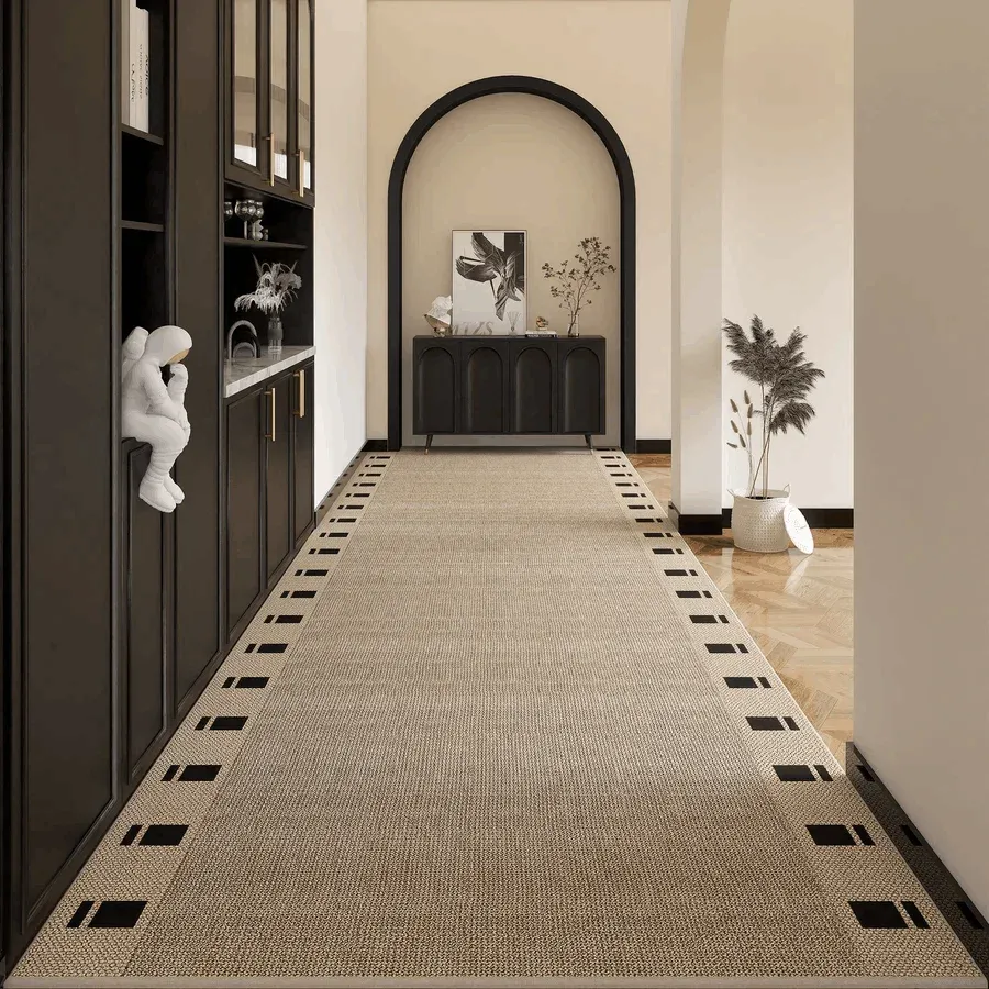 A long, textured beige sisal washable hallway runner rug featuring a modern black geometric border with square and dashed line patterns.