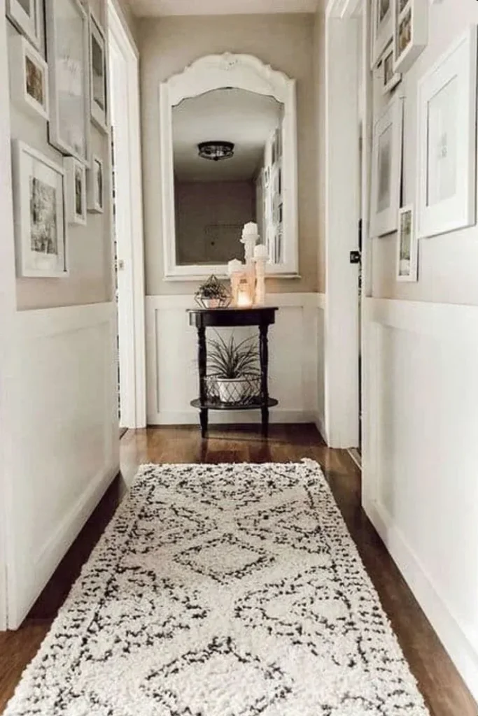 A cozy, textured cream shag narrow hallway runner rug featuring a black geometric diamond and dotted pattern, laid out on dark hardwood flooring.