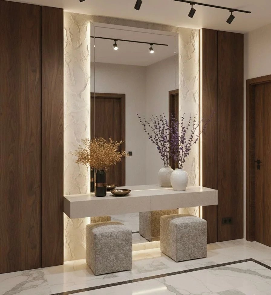 Luxury entryway featuring a floating marble console table beneath a large floor-to-ceiling mirror, framed by warm wood paneling, textured white stone walls, and hidden LED strip backlighting.