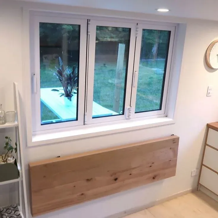 White three-panel window with a natural wood fold-down desk mounted on the wall directly beneath.